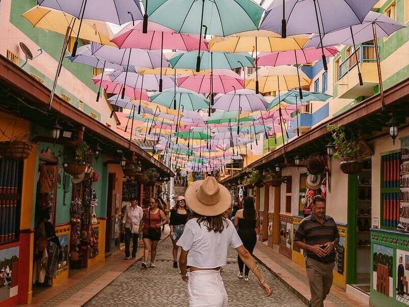 A street in Jard&iacute;n hung with coloured umbrellas between painted balconies